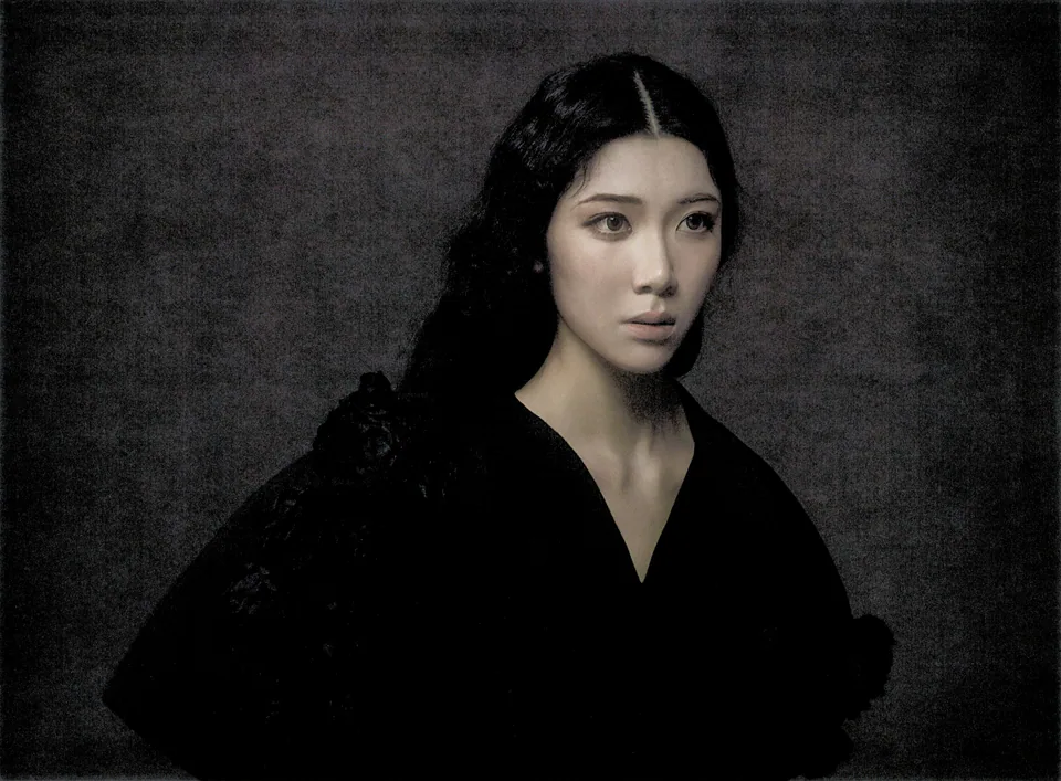 Close portrait of Sammi Chen in black against a textured charcoal backdrop.